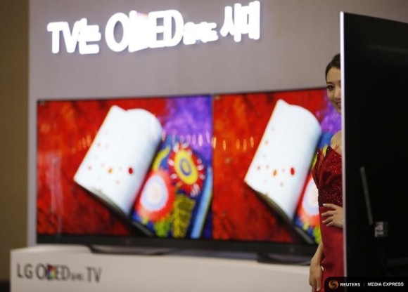 A model poses in front of LG Electronics' flexible organic light-emitting diode (OLED) TV sets, which are made with LG Display flat screens, during the 2014 Korea Electronics Show in Goyang October 17, 2014. REUTERS/Kim Hong-Ji